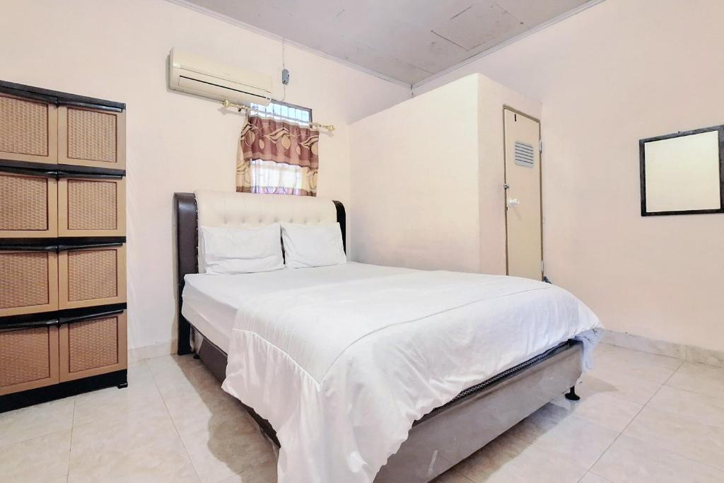 DukuHandira Homestay Syariah Padang RedPartner的一间卧室配有一张带白色床单的床和一扇窗户。