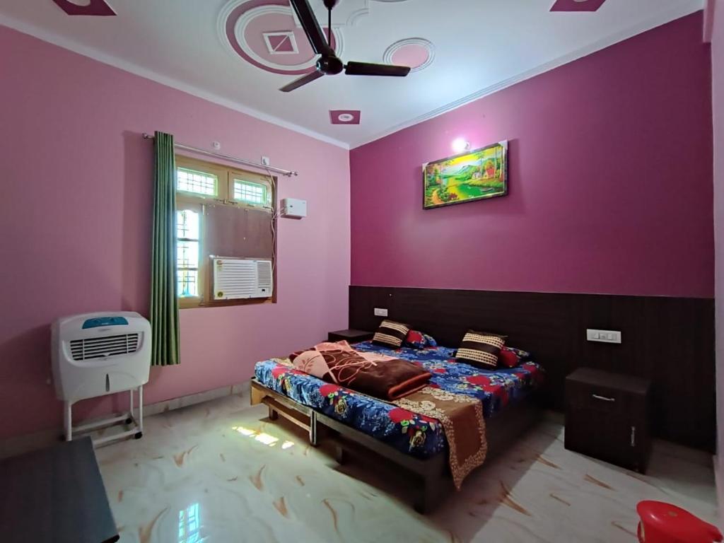 ShivpuriRatan Homestay的一间卧室设有紫色的墙壁和一张带风扇的床。