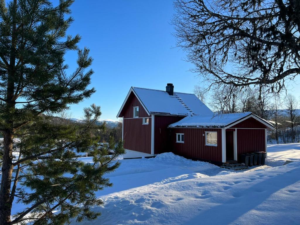 RaulandApartment Grønlid的雪中的一个红谷仓,有棵树