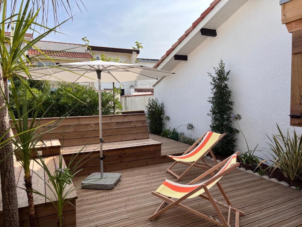 塞尼奥斯Ocean Lodge_plage Bourdaines的木制甲板上的两把椅子和一把遮阳伞