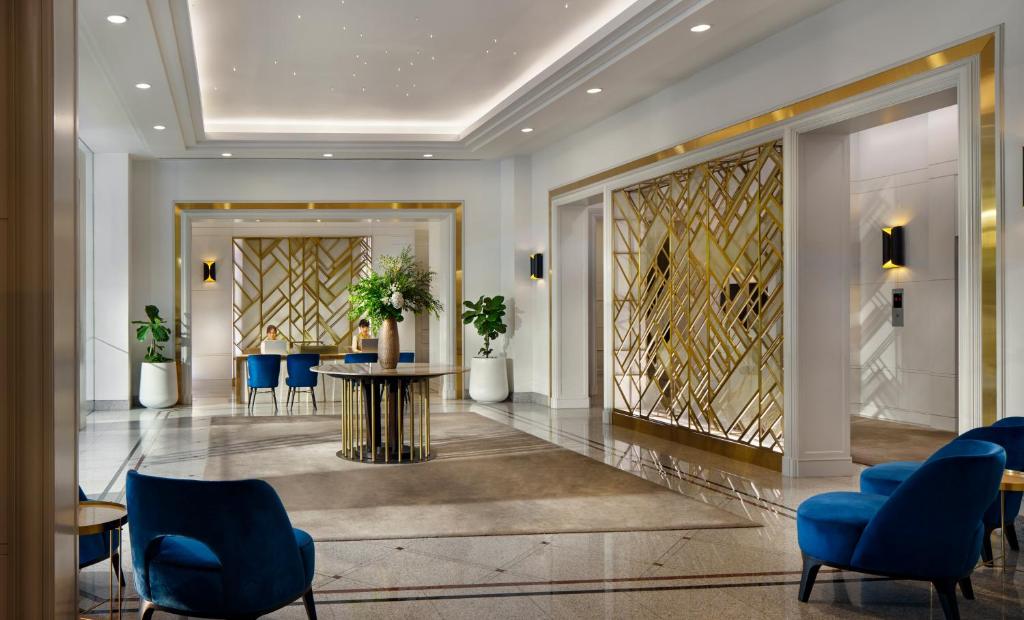 曼谷毕里斯顿苏安园景酒店 - SHA Plus的大堂设有蓝色椅子和桌子,位于大楼内