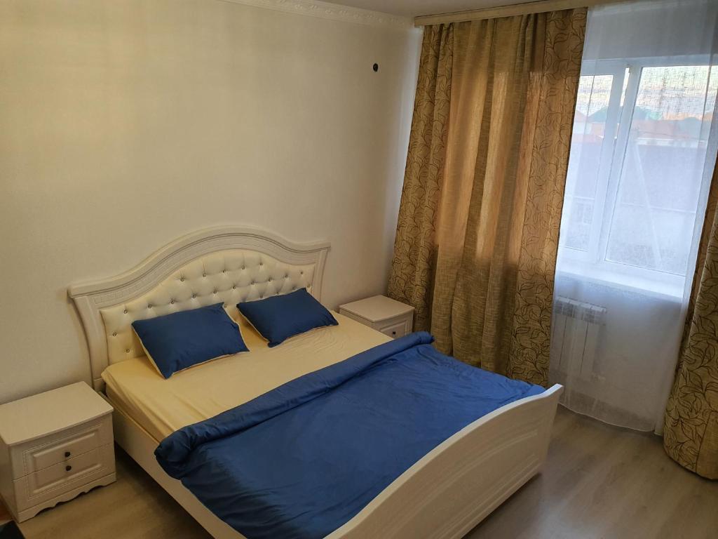 阿克托比2-ух комнатная квартира Юнис Сити г.Актобе的一间卧室配有一张带蓝色枕头的床和一扇窗户。