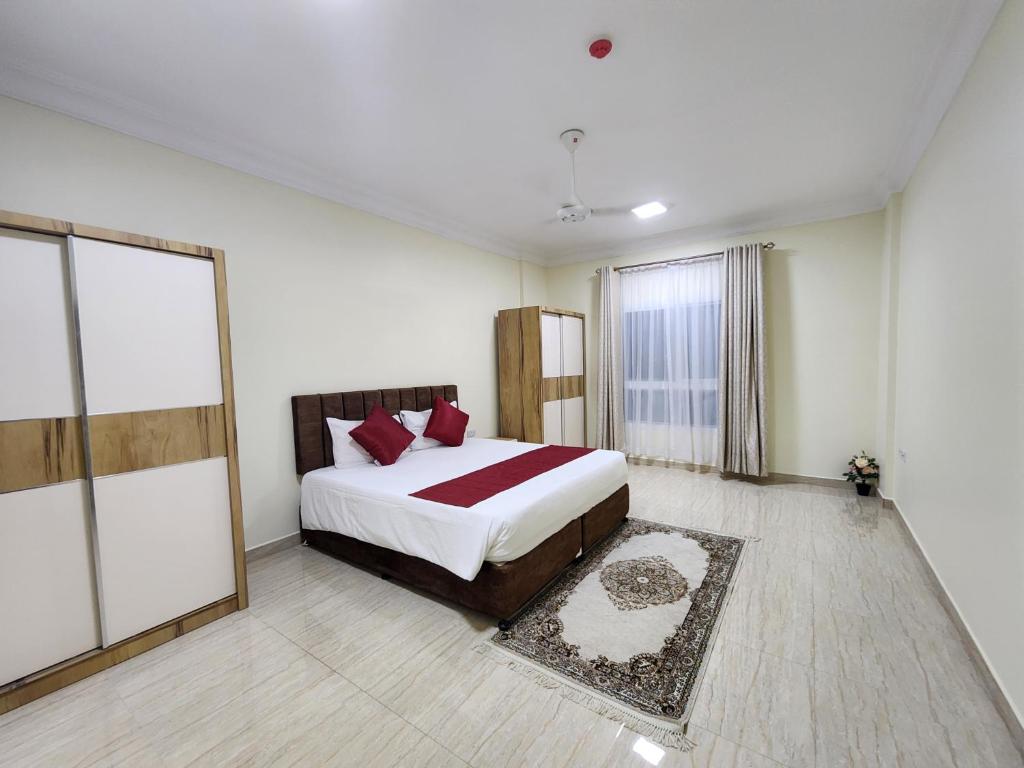 索哈尔Sohar Hotel - فندق صحار的一间卧室配有一张带红色枕头的大床