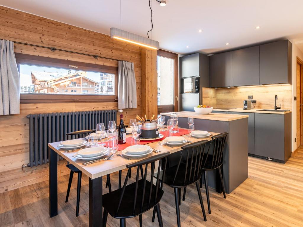 蒂涅Apartment Le Pramecou - Val Claret-8 by Interhome的厨房配有带椅子的长桌和厨房四柱床
