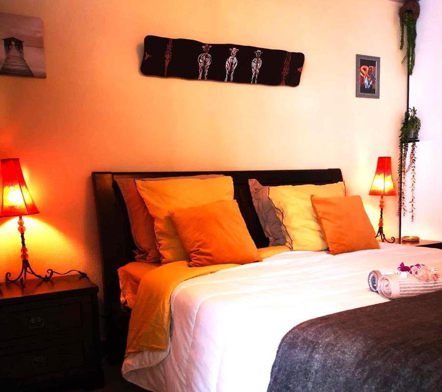 勒唐蓬Le Panoramique Loft的一间卧室配有一张带橙色枕头的床和两盏灯。
