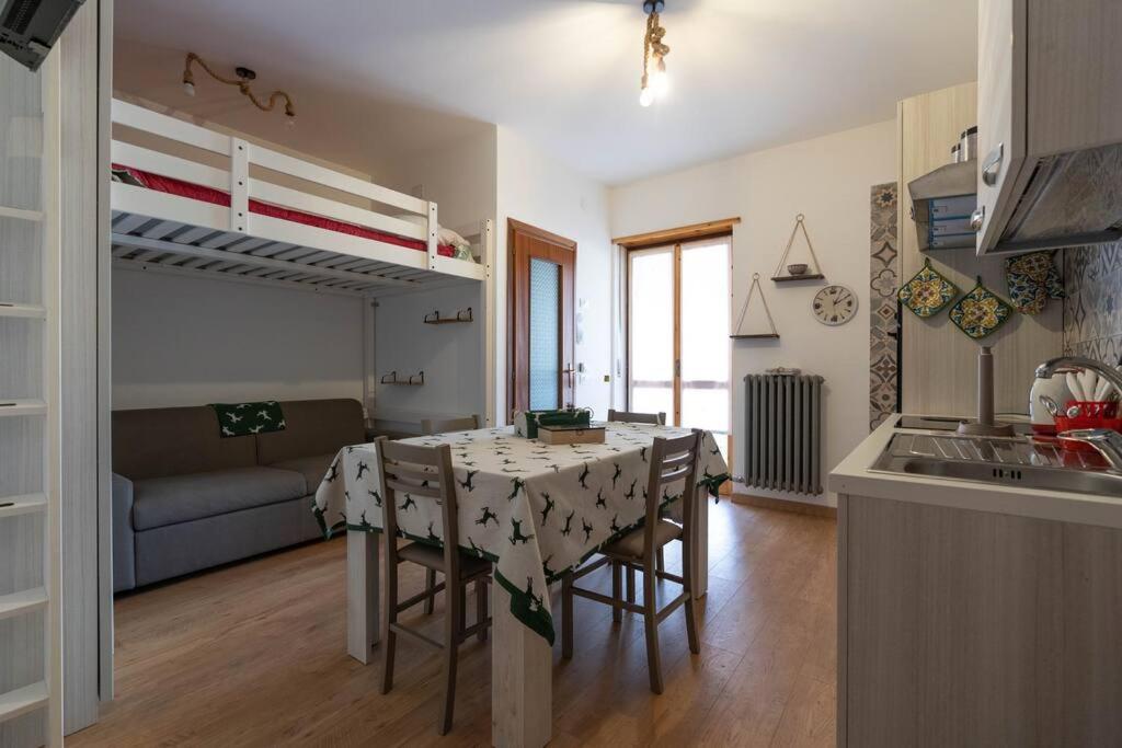 弗拉博萨索塔纳Rifugio a 15min dalle piste da sci的厨房以及带桌椅的起居室。