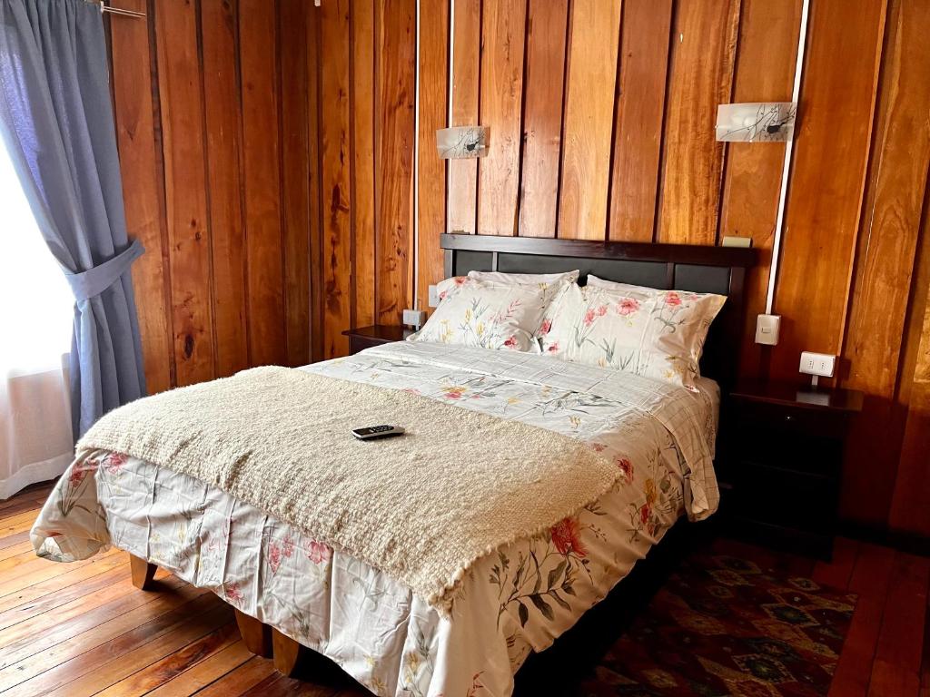 梅利佩乌科Hostal siete colores, Melipeuco的一间卧室配有一张木墙床