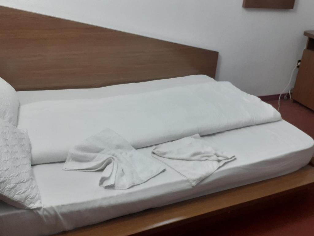 Hanul Anitei La paducel的一张铺有白色床单的床和木制床头板