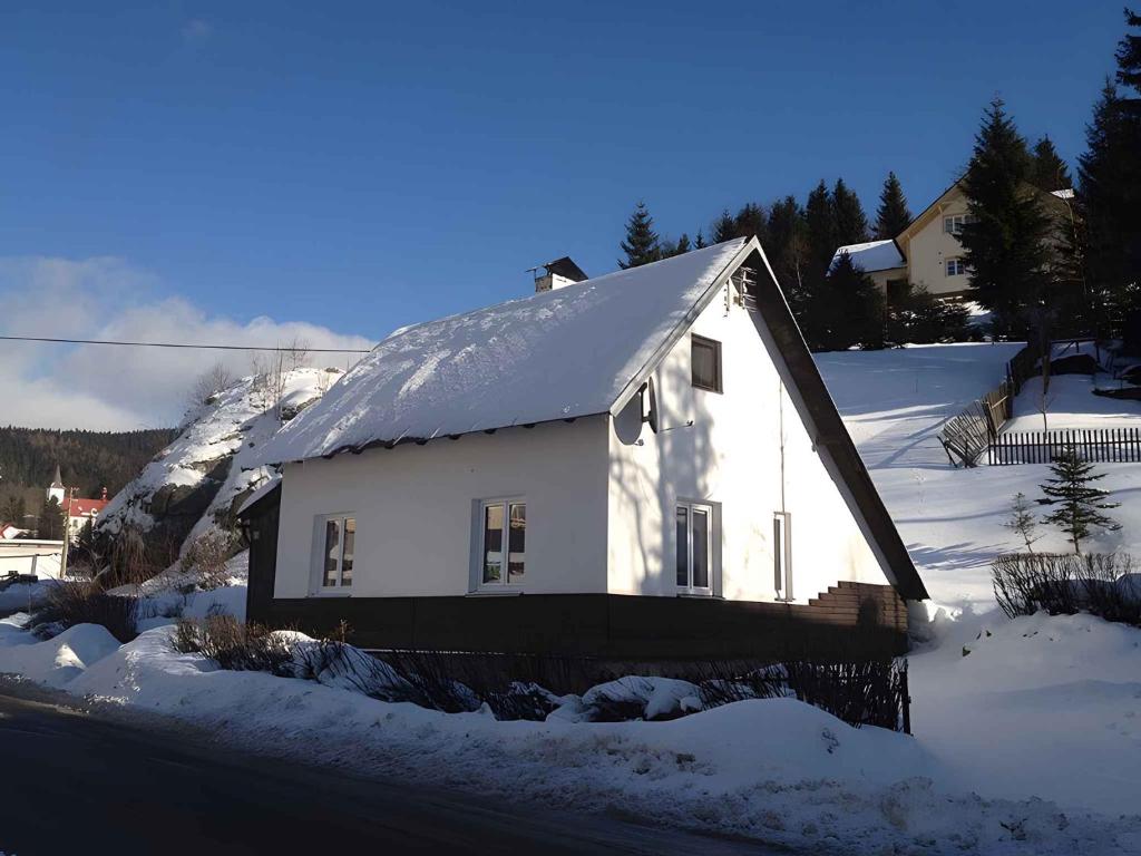 Nové HamryHoliday home Nove Hamry/Erzgebirge 1646的一座白色的小房子,上面有雪