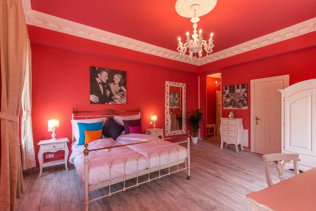 魏玛奥博格吉安卡洛大酒店的一间卧室设有红色的墙壁和一张带吊灯的床。