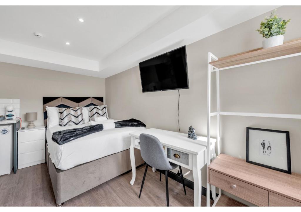 伦敦Stay & Explore: Convenient Studio - Prime Location的一间卧室配有一张床、一张书桌和一台电视。