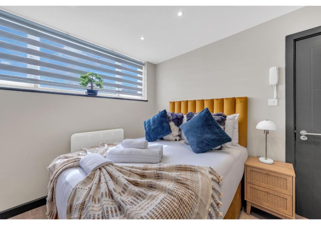 伦敦Get Your Zen On: Relaxing Studio in Central的一间卧室配有一张带蓝色枕头的床和一扇窗户。