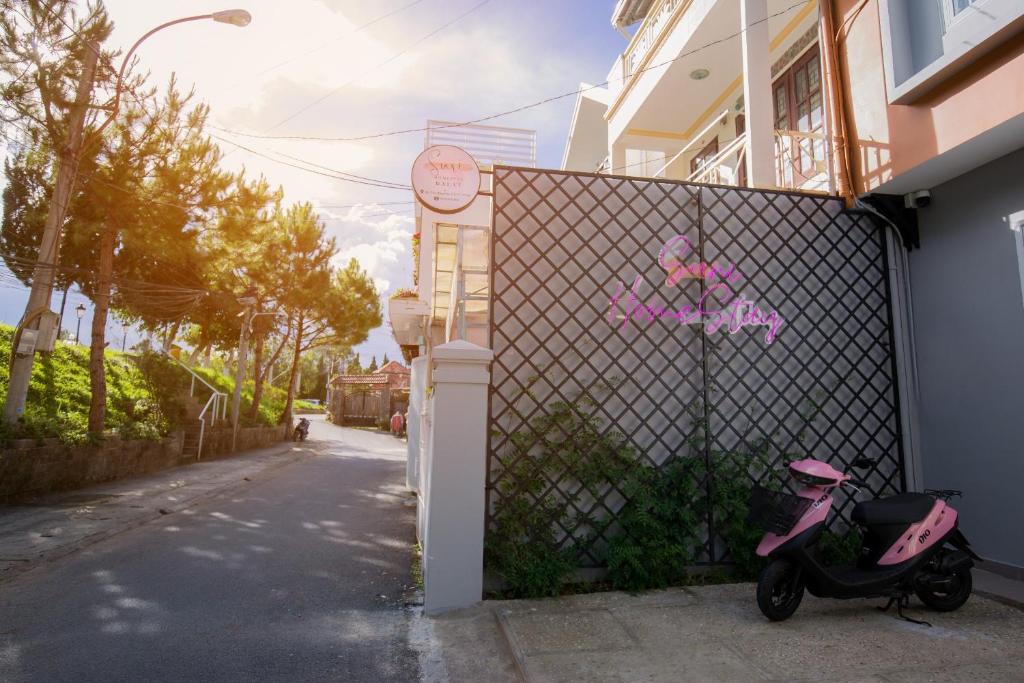 大叻Suri Homestay的停在围栏旁的粉红色摩托车
