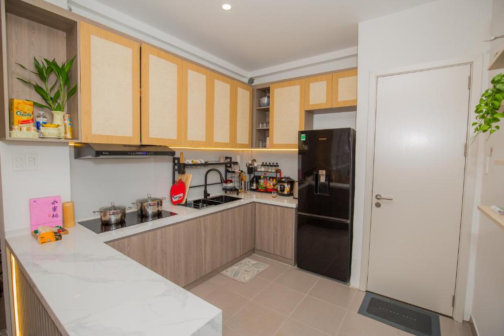 大叻Suri Homestay的厨房配有黑色冰箱和木质橱柜