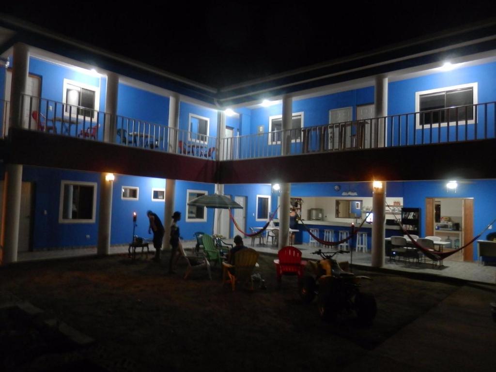 马那瓜Montecristi Hotel Near the Nicaragua Intl Airport的蓝色的建筑,人们在晚上坐在庭院里