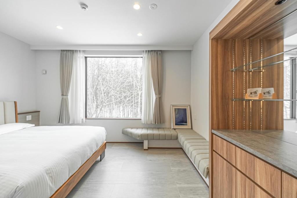 二世古Villa Yin Niseko的一间卧室配有一张床、一张沙发和一个窗口