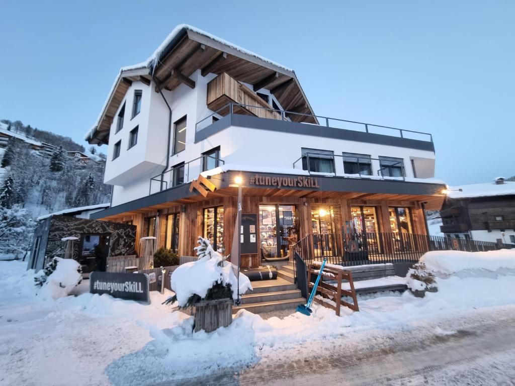 萨尔巴赫SKILL Mountain Lodge - Ski und Bike Hostel inklusive JOKER CARD的前面的地面上积雪的建筑