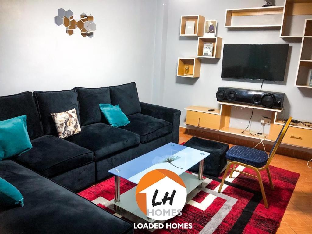 KikuyuLoaded homes的客厅配有黑色沙发和电视