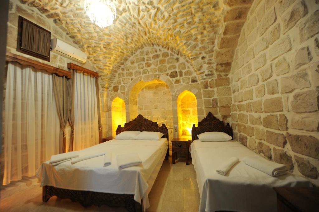 马尔丁ARTUKHAN BUTİK HOTEL的一间卧室设有两张床和石墙
