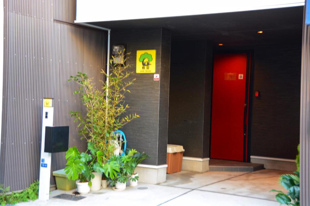 大阪WestHouse 天下茶屋店的植物丛生的建筑物前的红色门