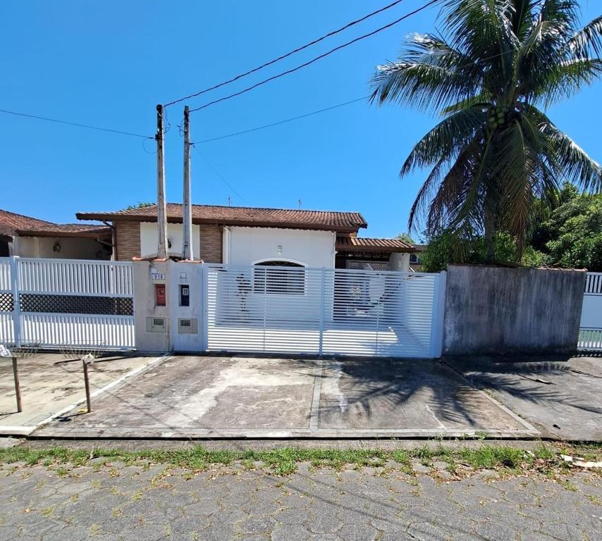 佩鲁伊比CASA DE PRAIA MARAVILHOSA PERUIBE的棕榈树屋前的白色围栏