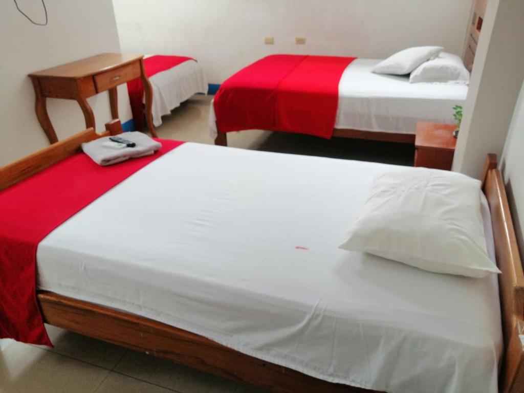 阿约拉港Descanso del Petrel的客房内的两张床,配有红色和白色床单