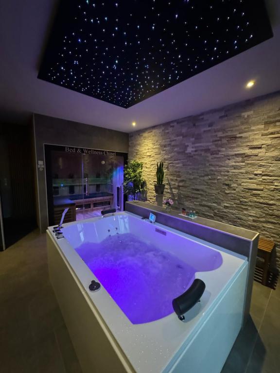 圣安娜兰Bed & Wellness Chinel Luxe vakantiehuis met Sauna's en Bubbelbad的浴室设有石墙和紫色浴缸