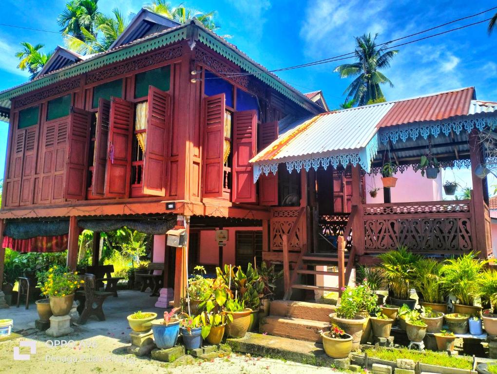 甲抛峇底Homestay Teratak Kayu kota Aur的一座色彩缤纷的房子,前面有盆栽植物
