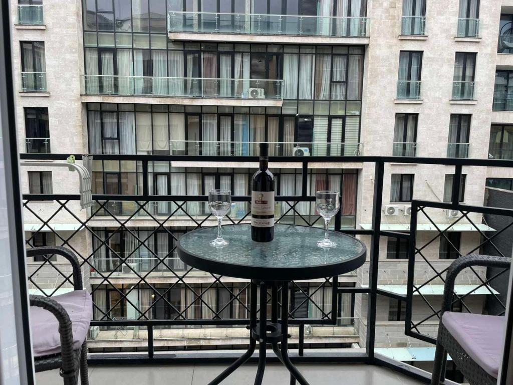 第比利斯Paliashvili 90 - VAKE Park 2BR Apartment的阳台上的桌子上放着一瓶葡萄酒和两杯酒