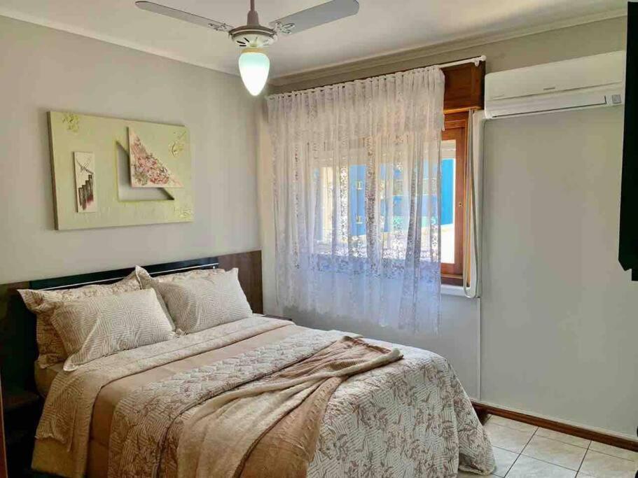 卡庞达卡诺阿Apartamento 2 quadras do mar centro Capão da Canoa的一间卧室设有一张大床和一个窗户。