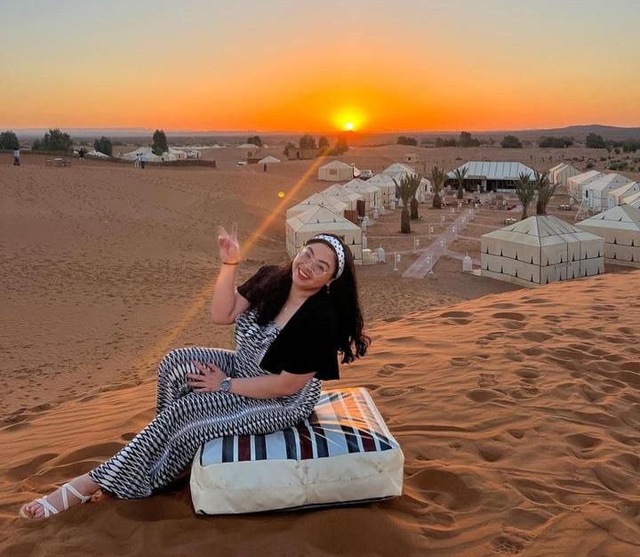 梅尔祖卡Merzouga Top Luxury Camp的坐在沙漠床边的女人