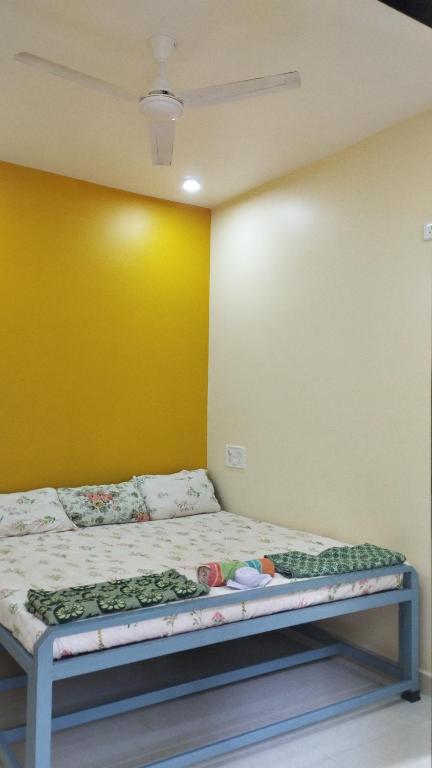 马尔万आंगण होम स्टे的黄色墙的房间里一张床位