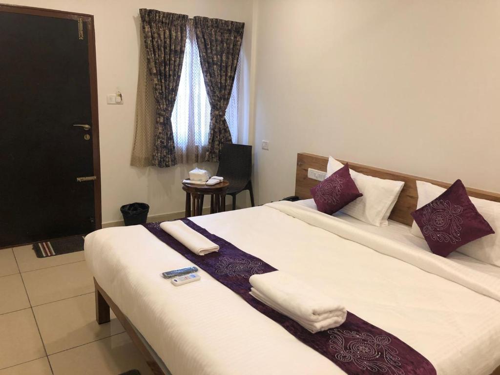班加罗尔Hotel Amulya Regency的一间卧室配有一张大床,提供紫色和白色枕头