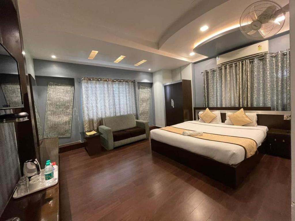 西里古里Hotel Sundaram Palace的一间卧室,卧室内配有一张床和一把椅子