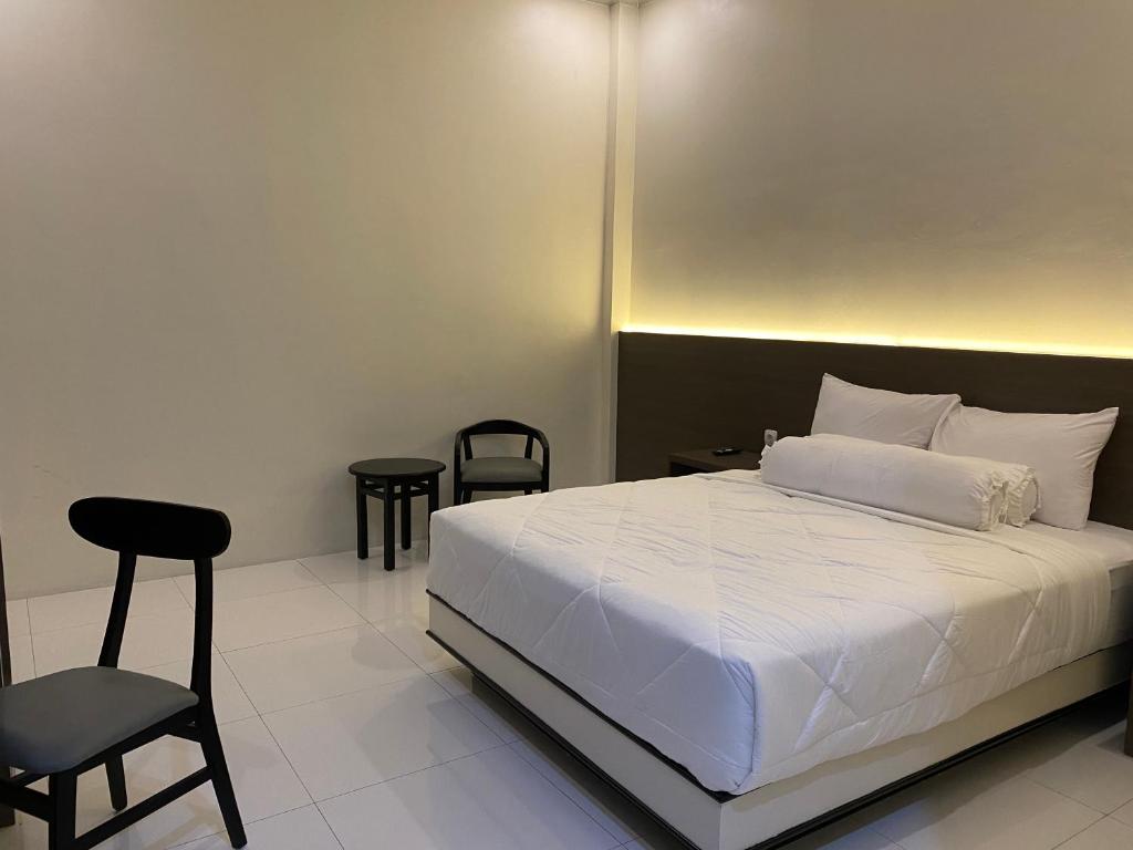 TjolomaduGenio Syariah Hotel Solo的卧室配有白色的床和椅子