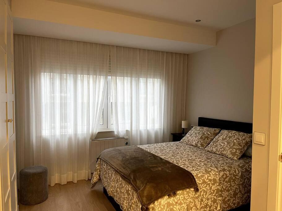 费罗尔Piso en el centro de Ferrol recién reformado.的一间卧室配有床和带窗帘的窗户