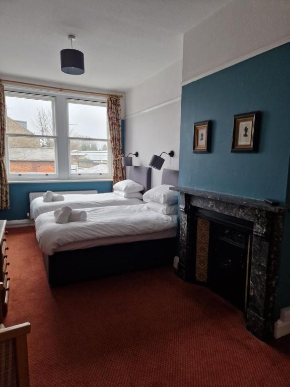 法弗舍姆Railway Hotel的一间卧室设有两张床和一个壁炉