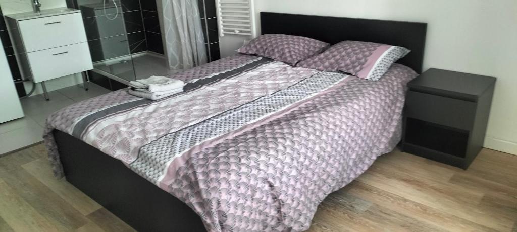 Rive-de-GierAppartement 2 pièces的一间卧室配有一张大床、紫色棉被和枕头