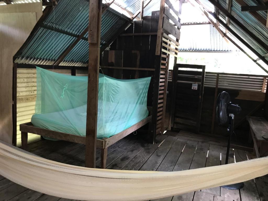 莱蒂西亚Casa do Xingú的带屋顶的客房内的吊床