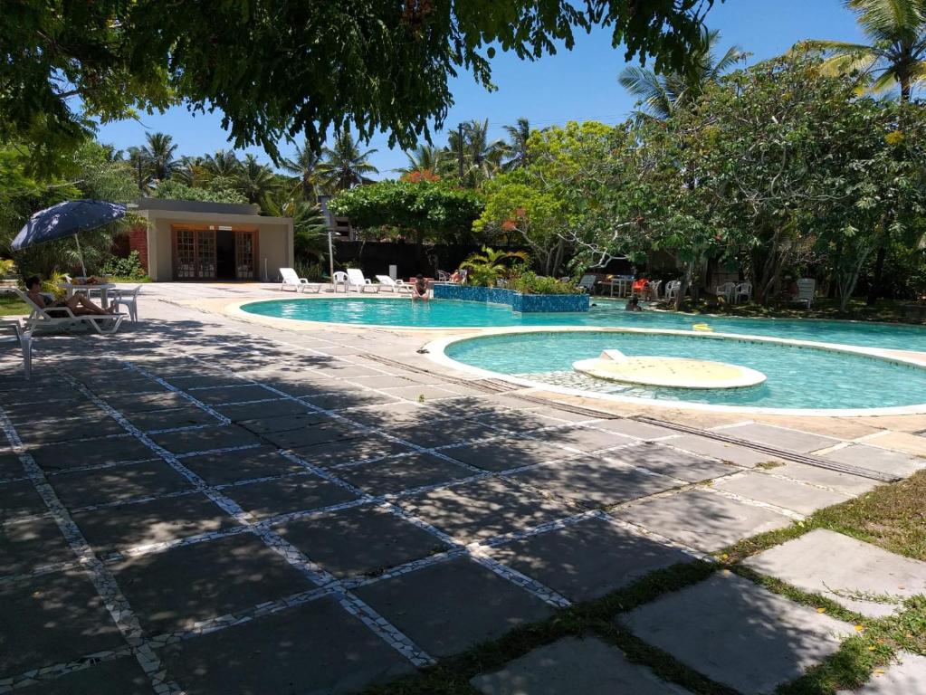阿尔科巴萨Condomínio das gaivotas的一座带树木和椅子的度假村内的游泳池