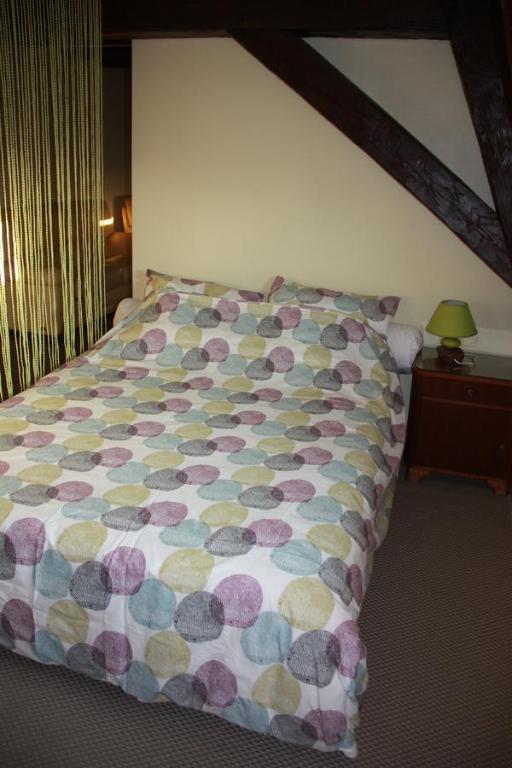 萨维尔纳切斯萨宾洛朗旅馆的卧室内一张带五颜六色棉被的床