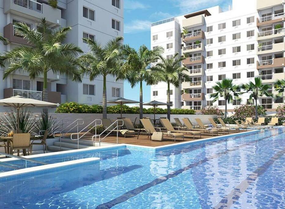 里约热内卢Excelente apartamento a 5 minutos da praia e shopping的一座带椅子和棕榈树的度假村游泳池