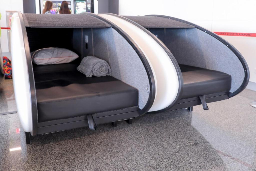 华沙Sleeping Pods GoSleep - Inside of Warsaw Chopin Airport, non schengen restricted zone after passport control, near Gate 2N的一间设有2个座位的房间,位于一栋带床的建筑内