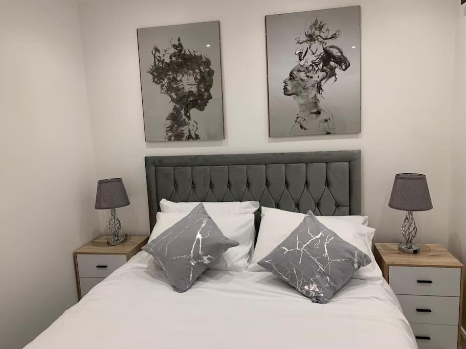 CarshaltonApartment C, a one bedroom Flat in south London的一间卧室配有一张带枕头的床和两盏灯。