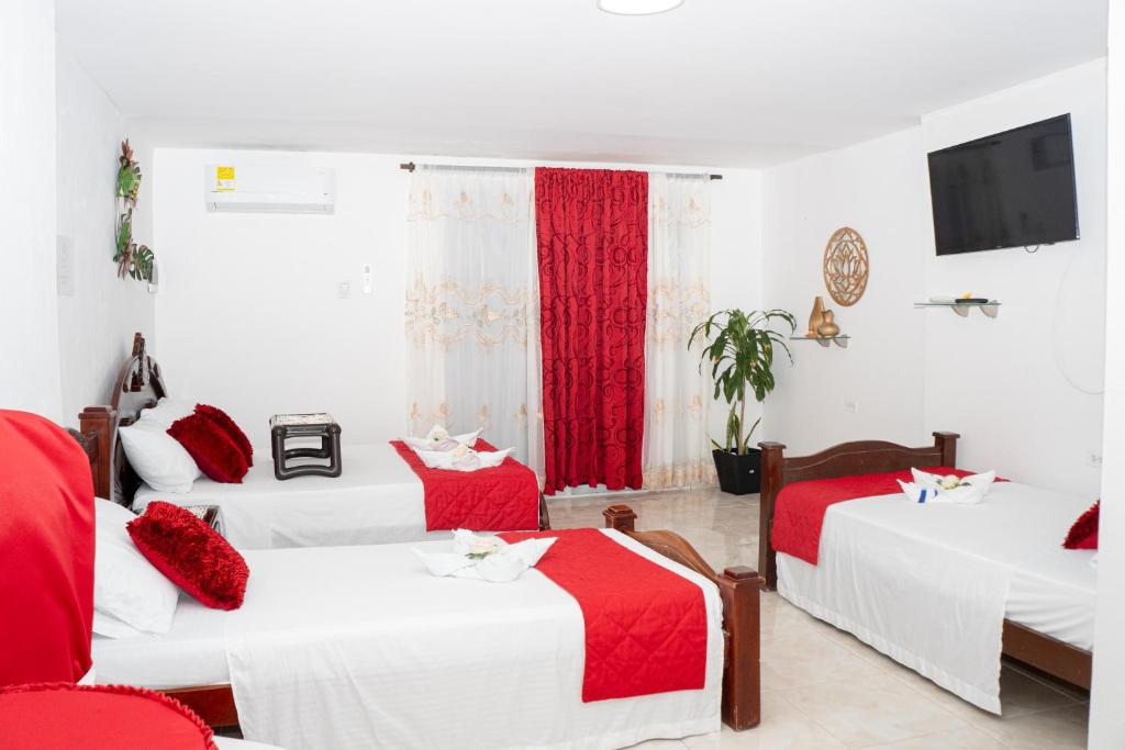 哥伦比亚港La Niña Mire的一间设有三张红色和白色床单的房间