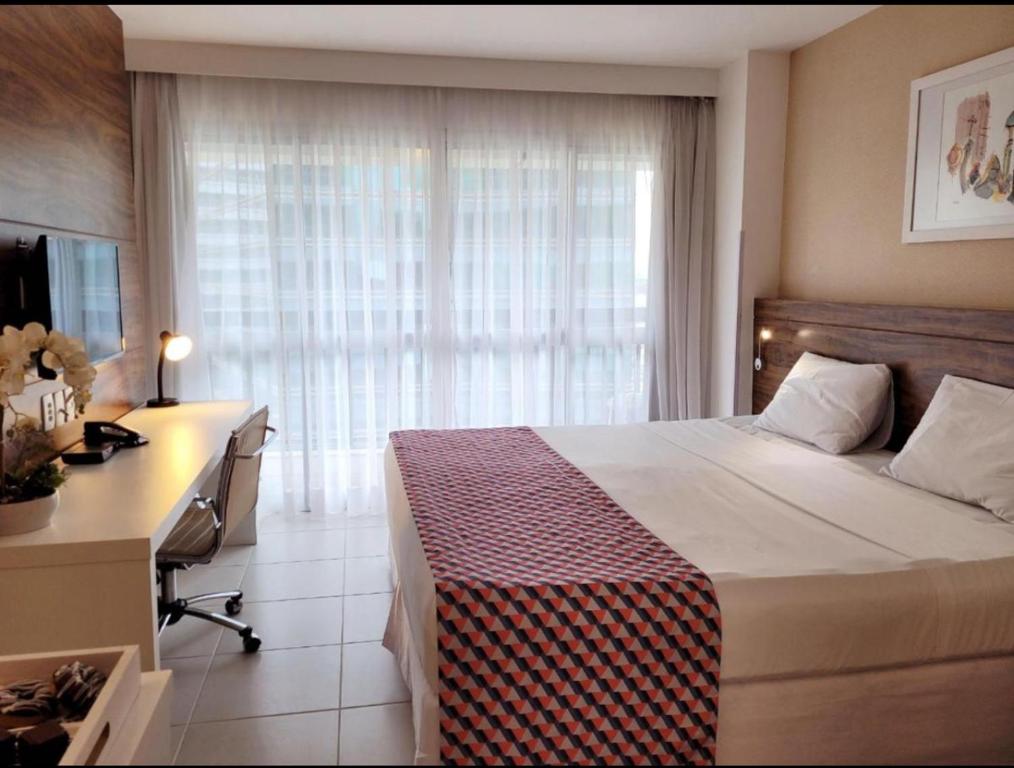 巴西利亚Hotel Vision的一间卧室配有一张床、一张书桌和一个窗户。