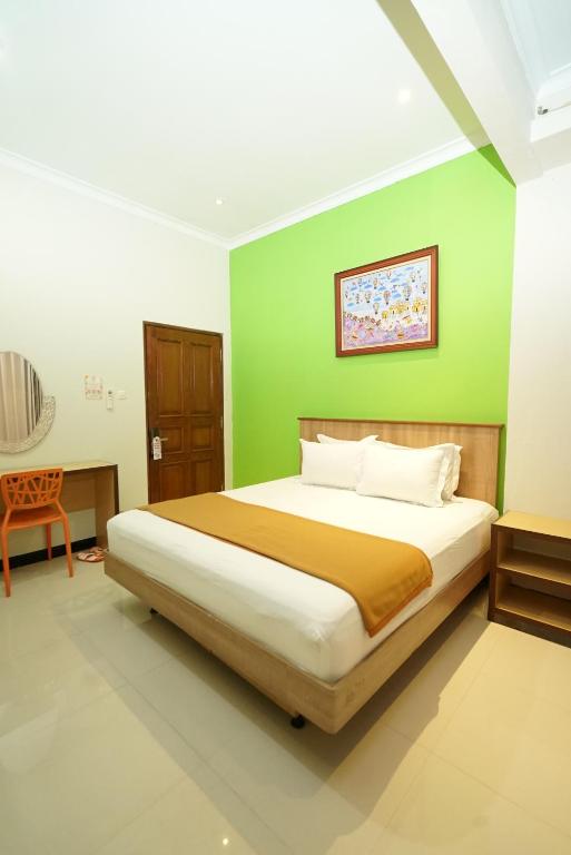日惹The Cabin Hotel Ngupasan的一间卧室配有一张带绿色墙壁的床