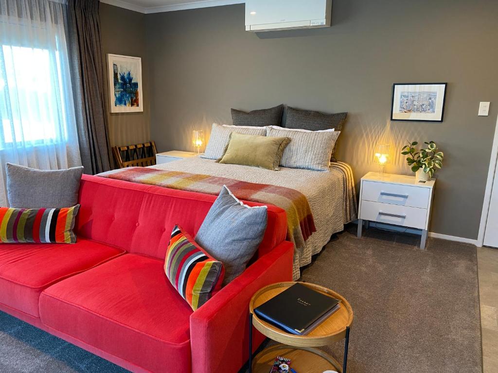 新普利茅斯Escape的一间卧室配有一张床和一张红色的沙发