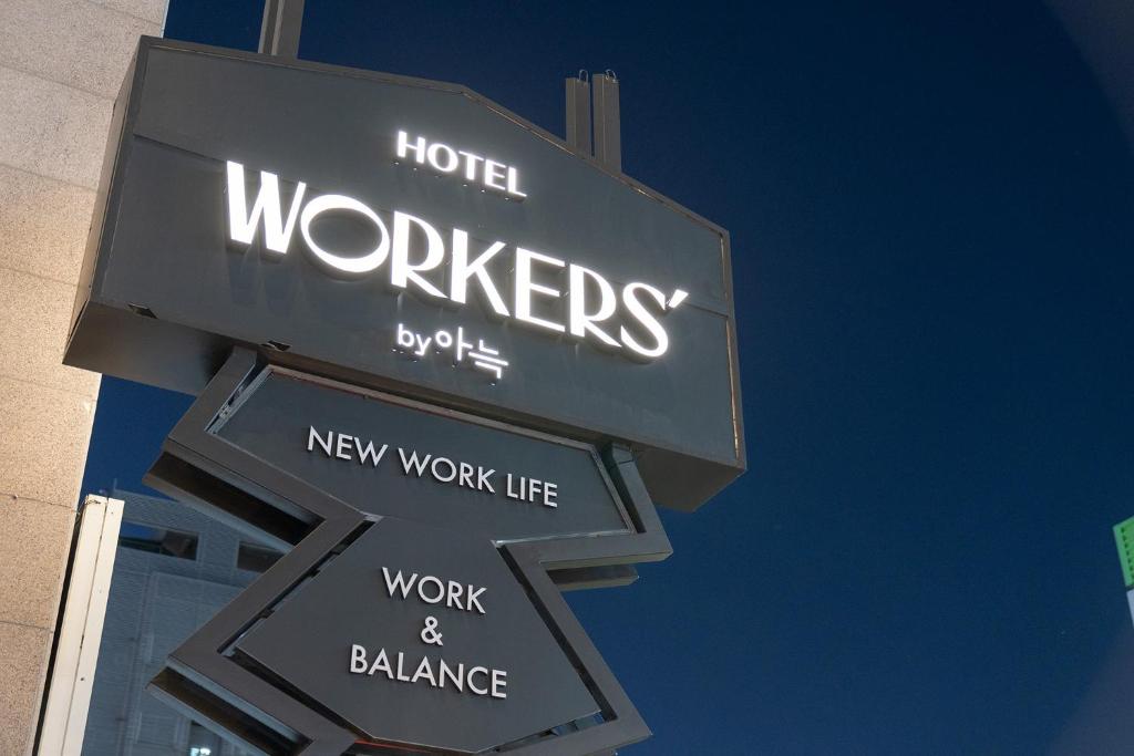 大田Workers Hotel Daejeon by Aank的一家旅馆工人的标志,带有箭头