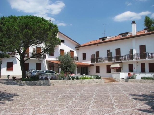 西斯蒂亚纳Hotel Alla Dolina的前面有一棵树的白色大建筑